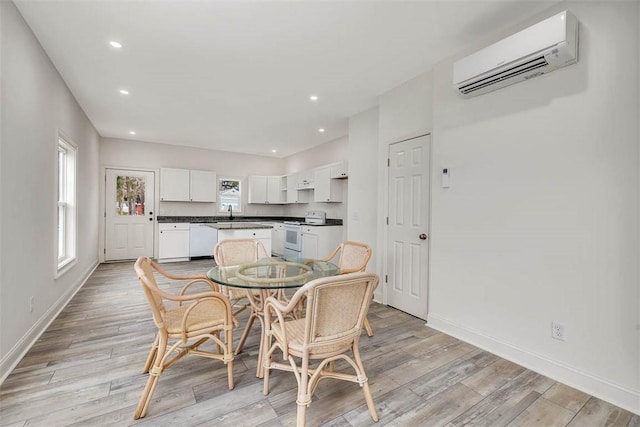 dining room with a wall unit AC and light hardwood / wood-style floors