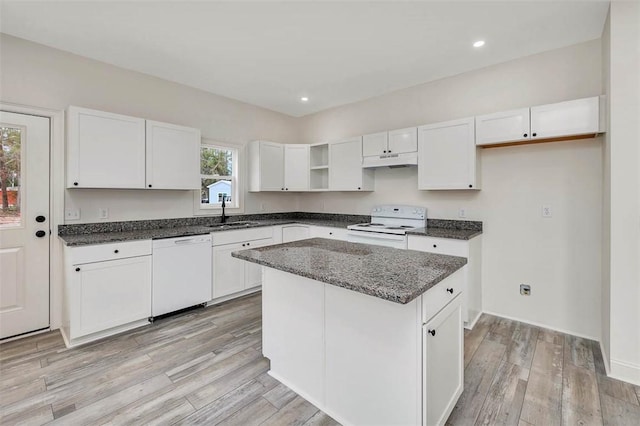 kitchen featuring white appliances, white cabinets, a center island, and light wood-type flooring