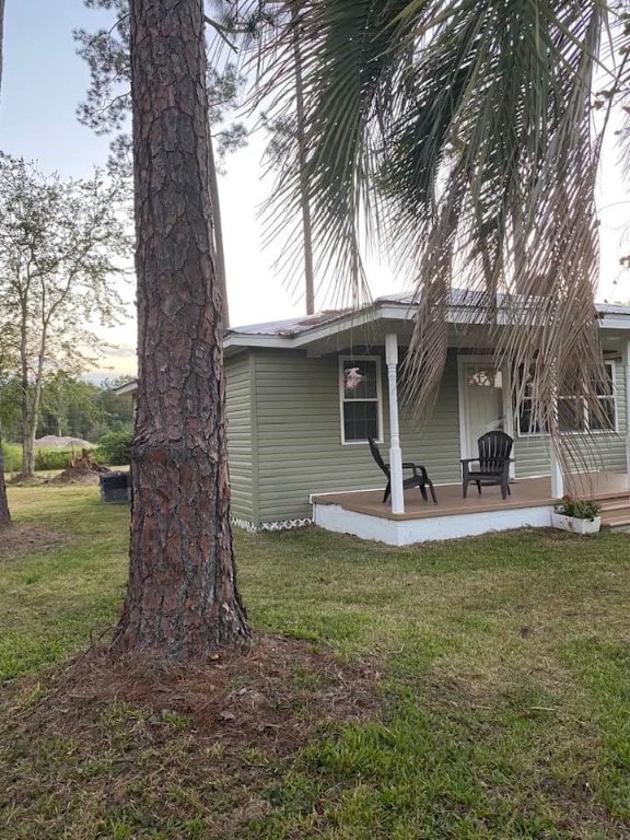 back house at dusk with covered porch and a yard