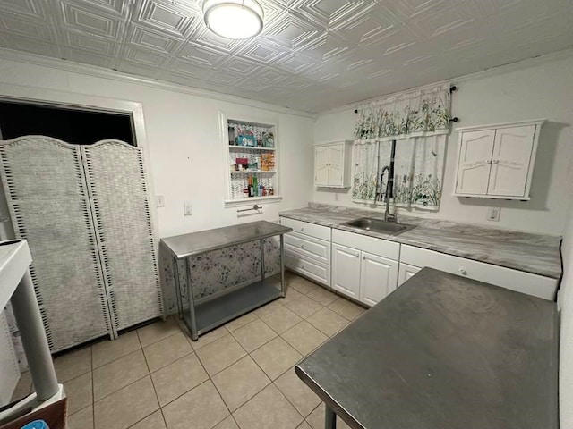 kitchen featuring white cabinets, light tile patterned flooring, and sink