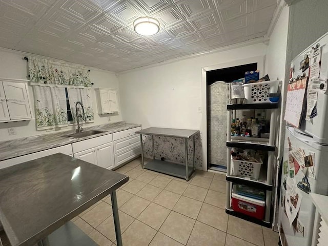 kitchen featuring white cabinets, light tile patterned flooring, and sink