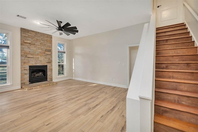 unfurnished living room with visible vents, a ceiling fan, light wood-style floors, stairway, and plenty of natural light