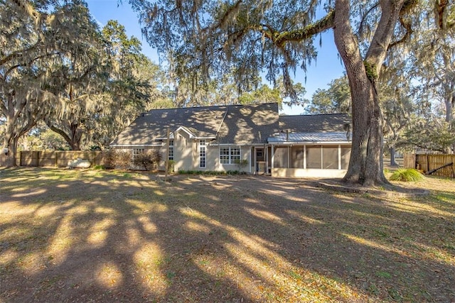 view of front of property featuring a front lawn, fence, and a sunroom