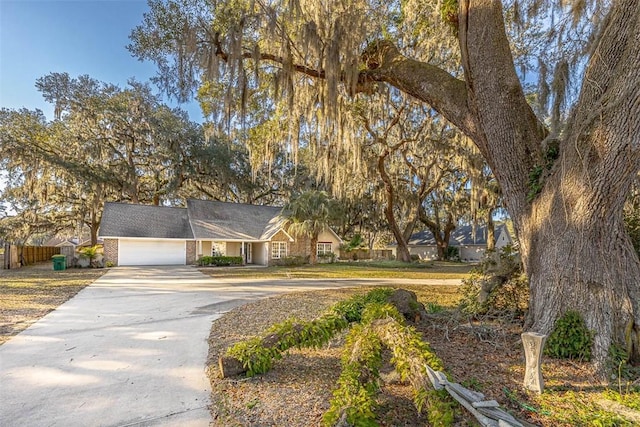 view of front of house with a garage, fence, concrete driveway, and brick siding