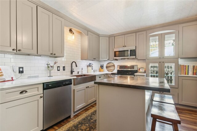 kitchen with a center island, sink, dark hardwood / wood-style floors, gray cabinets, and appliances with stainless steel finishes