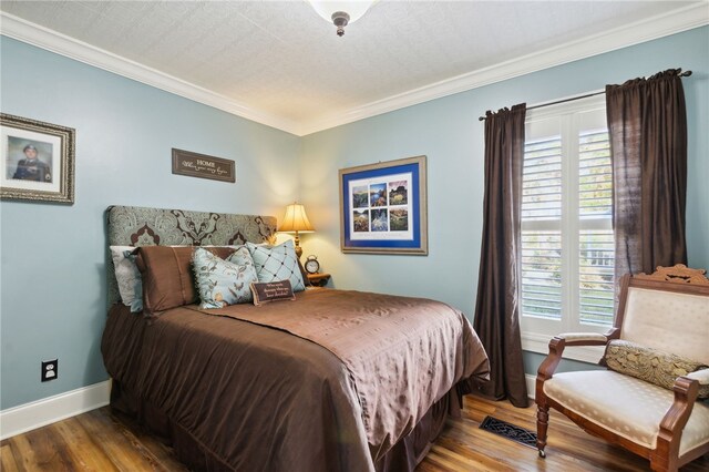 bedroom with a textured ceiling, wood-type flooring, and crown molding