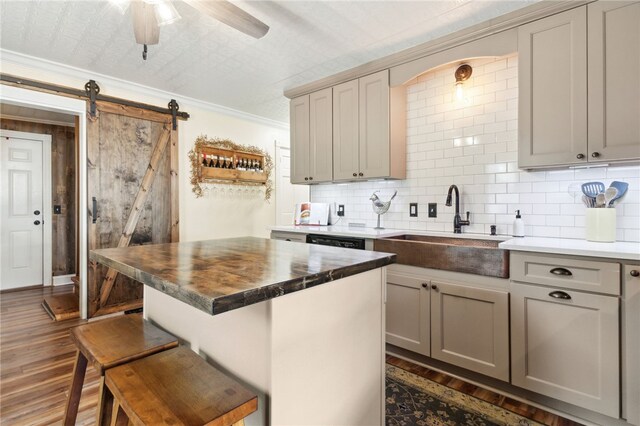 kitchen featuring a center island, sink, dark hardwood / wood-style floors, a barn door, and ornamental molding