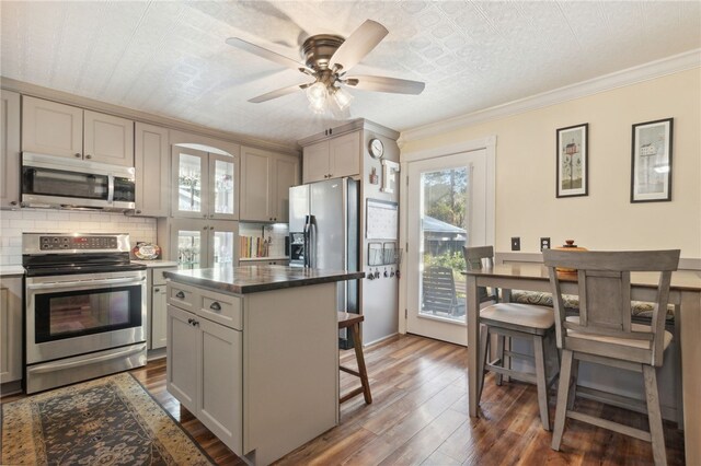 kitchen with a breakfast bar area, a kitchen island, dark hardwood / wood-style floors, and appliances with stainless steel finishes