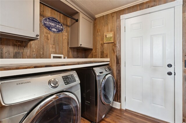 laundry area with cabinets, ornamental molding, hardwood / wood-style flooring, washing machine and dryer, and wood walls