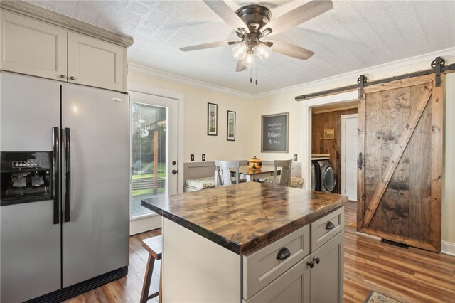 kitchen featuring wooden counters, stainless steel fridge with ice dispenser, a barn door, ornamental molding, and wood-type flooring