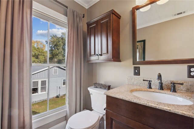 bathroom featuring a wealth of natural light, crown molding, vanity, and toilet