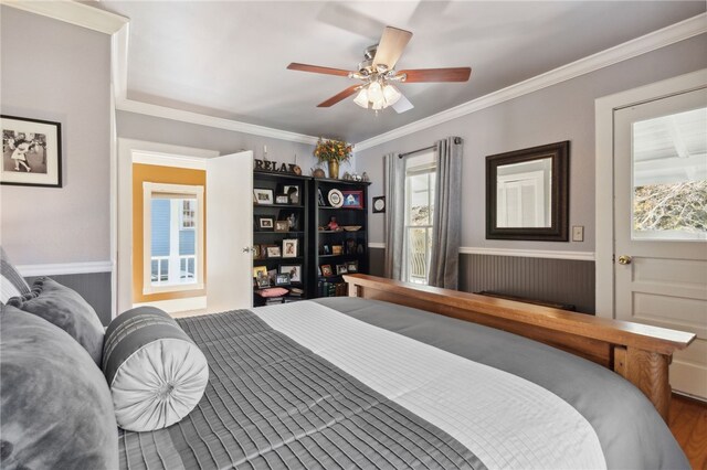 bedroom featuring multiple windows, ceiling fan, wood-type flooring, and ornamental molding