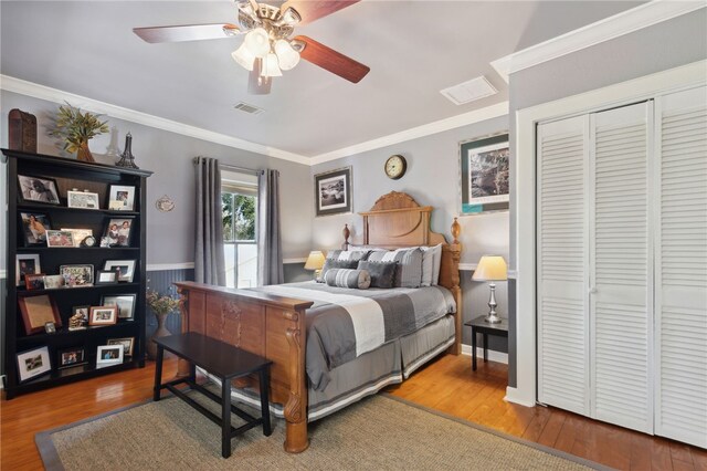 bedroom with hardwood / wood-style flooring, ceiling fan, ornamental molding, and a closet