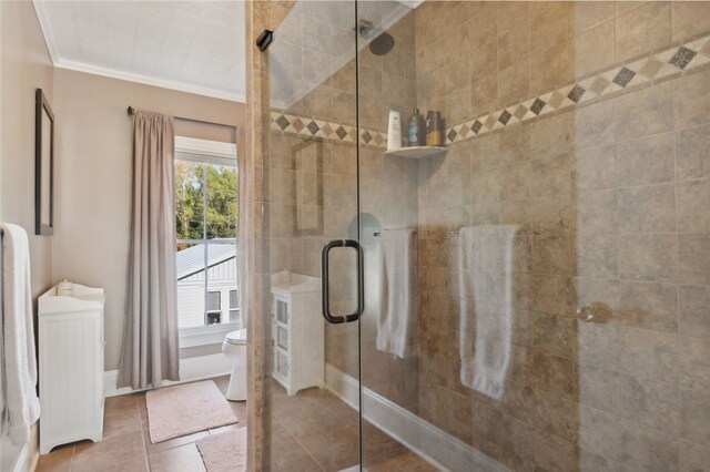 bathroom with toilet, tile patterned floors, an enclosed shower, and crown molding