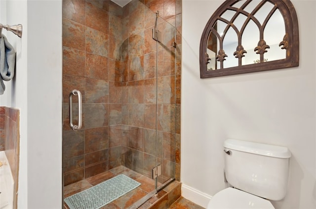 bathroom featuring a shower with door and toilet