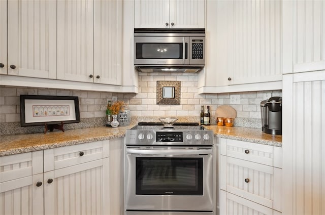 kitchen featuring white cabinets, decorative backsplash, light stone counters, and appliances with stainless steel finishes