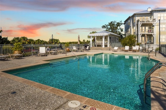 pool at dusk with a patio area