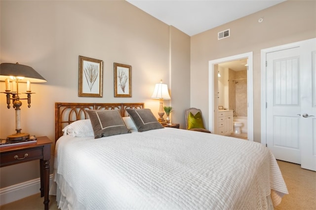 bedroom with ensuite bathroom and light carpet