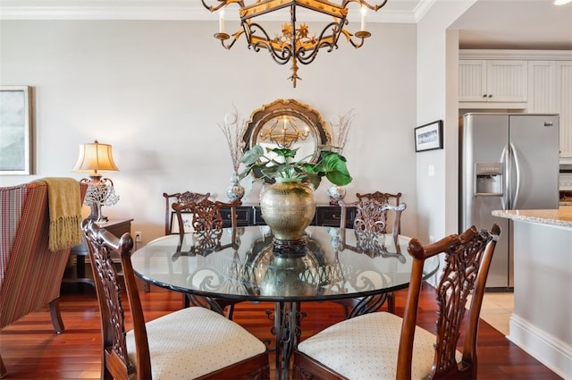 dining space with wood-type flooring, a notable chandelier, and ornamental molding