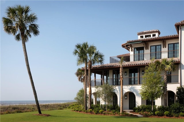 mediterranean / spanish-style home featuring a front lawn and a balcony