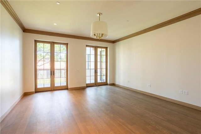 spare room featuring wood-type flooring, ornamental molding, and french doors