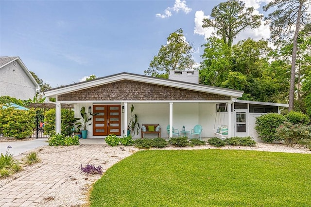 view of front of property featuring a front yard, covered porch, and french doors