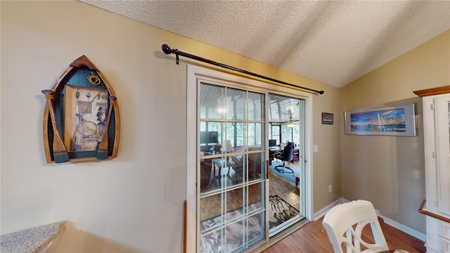 interior space featuring ceiling fan, wood-type flooring, a textured ceiling, and vaulted ceiling