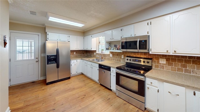 kitchen with appliances with stainless steel finishes, white cabinetry, a wealth of natural light, and sink