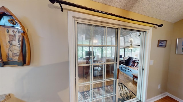 doorway featuring hardwood / wood-style flooring, ceiling fan, and a textured ceiling