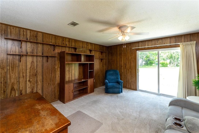 2320 Ben Hill Ave, Waycross, GA 31501 - living room featuring wood walls, light carpet, a ceiling fan, and a textured ceiling