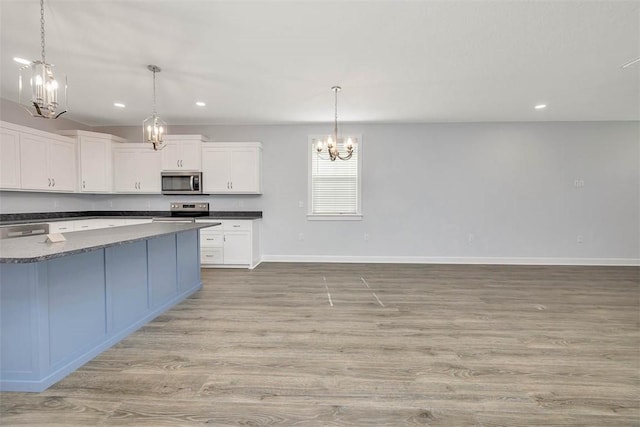 kitchen with white cabinets, stainless steel appliances, baseboards, recessed lighting, and a notable chandelier