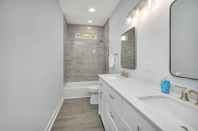 bathroom with toilet, double vanity, a sink, and wood finished floors