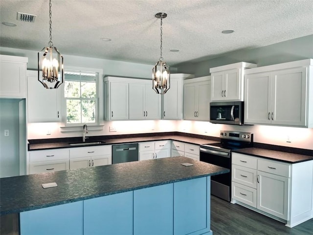 kitchen featuring decorative light fixtures, sink, white cabinetry, and appliances with stainless steel finishes