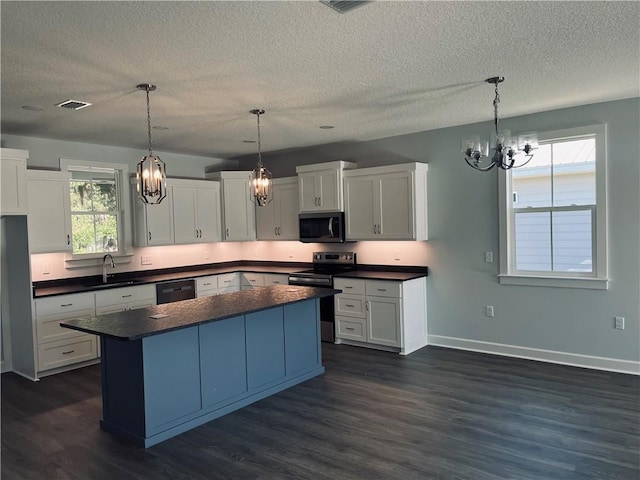 kitchen featuring decorative light fixtures, white cabinets, appliances with stainless steel finishes, and a center island