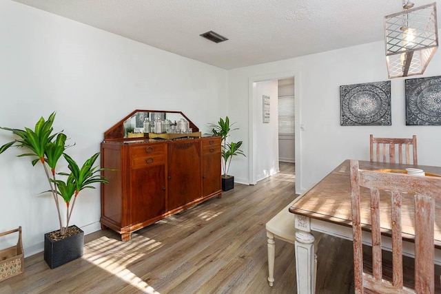 dining area with a textured ceiling and dark wood-type flooring