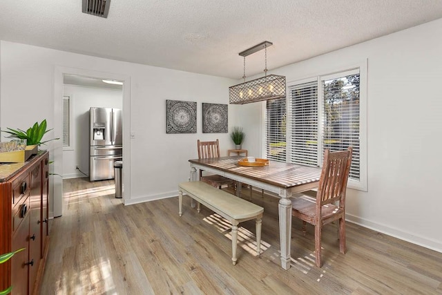 dining room with a textured ceiling and light hardwood / wood-style flooring