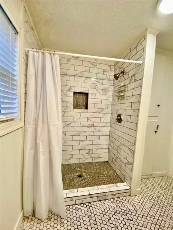 bathroom with a shower with curtain and a textured ceiling