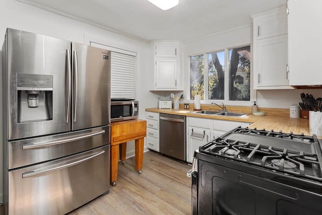 kitchen featuring white cabinetry, sink, stainless steel appliances, light hardwood / wood-style flooring, and ornamental molding