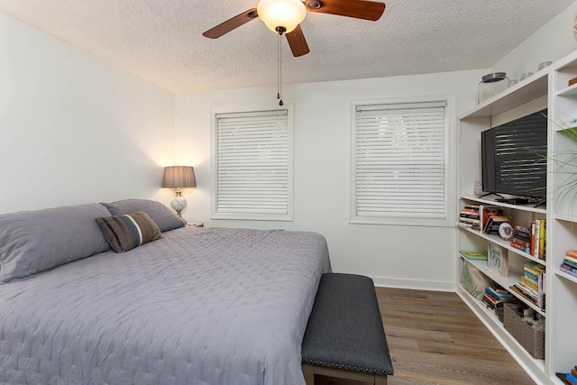 bedroom featuring ceiling fan, wood-type flooring, and a textured ceiling