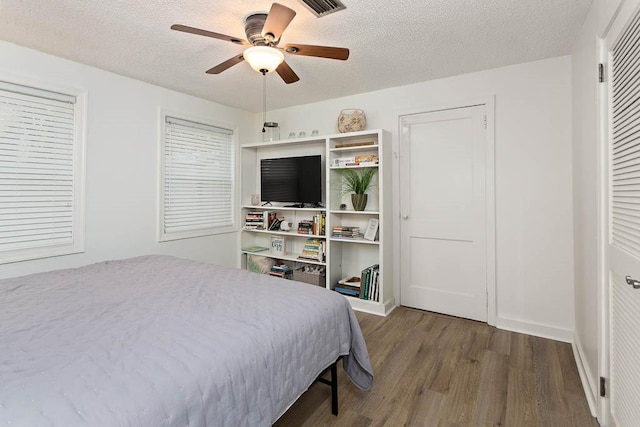 bedroom featuring ceiling fan, wood-type flooring, and a textured ceiling