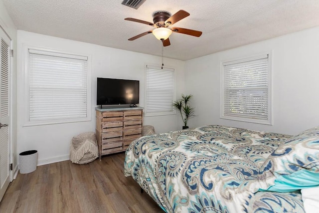 bedroom featuring ceiling fan, a closet, dark wood-type flooring, and a textured ceiling