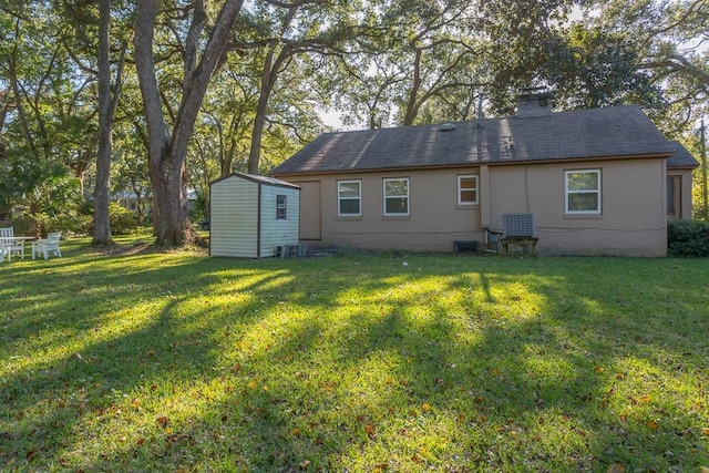 back of property with a lawn and a storage unit