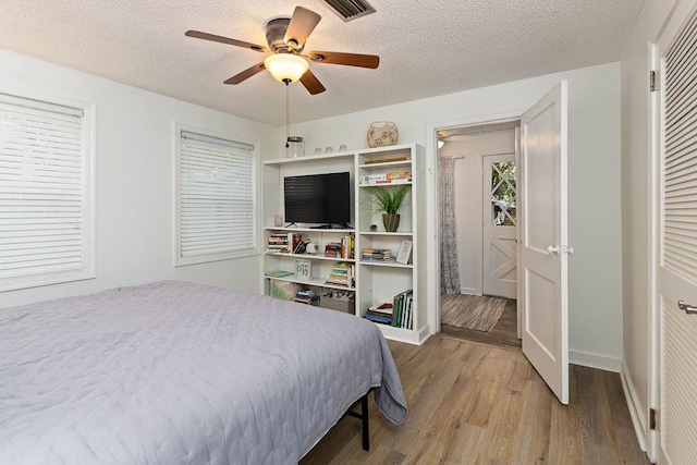 bedroom featuring ceiling fan, wood-type flooring, and a textured ceiling