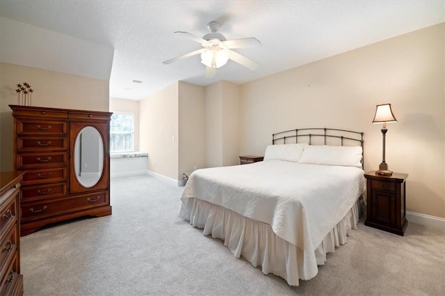 bedroom with light carpet, a textured ceiling, a ceiling fan, and baseboards