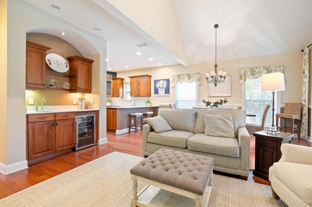 living room featuring hardwood / wood-style flooring, an inviting chandelier, and lofted ceiling with beams