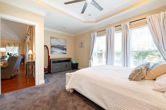 carpeted bedroom featuring a raised ceiling, crown molding, baseboards, and ceiling fan