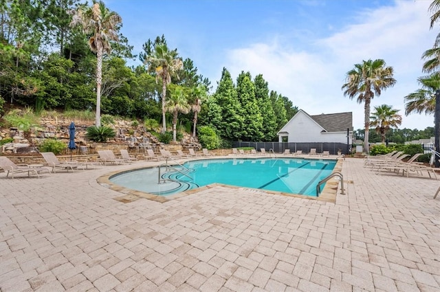 community pool with a patio area and fence