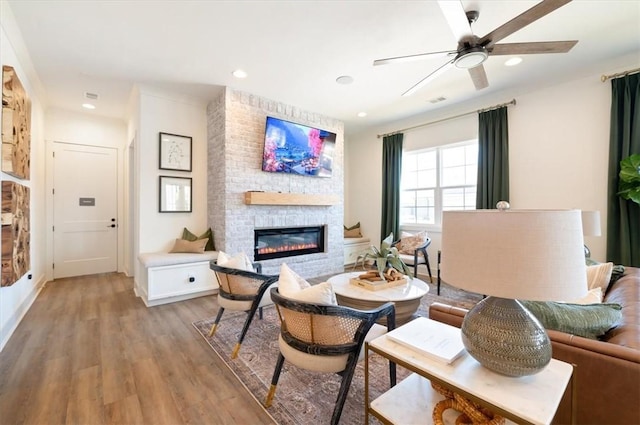 living area featuring light wood-style floors, recessed lighting, a fireplace, and a ceiling fan