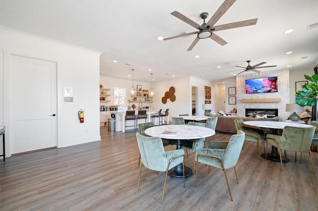 dining space featuring recessed lighting, a fireplace, wood finished floors, visible vents, and baseboards