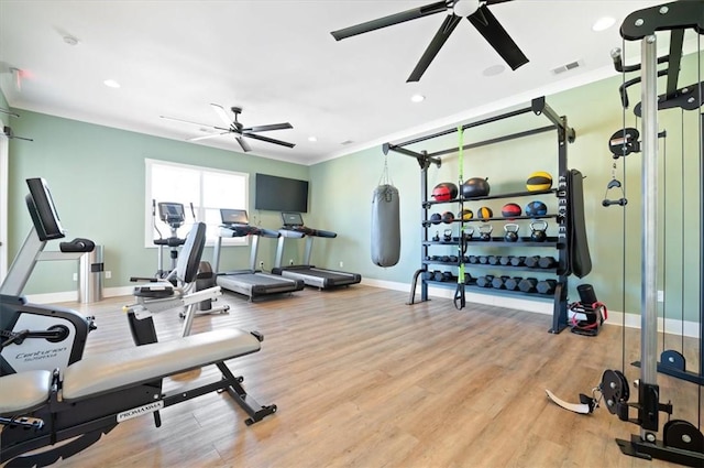 workout area featuring ceiling fan, wood finished floors, visible vents, baseboards, and crown molding